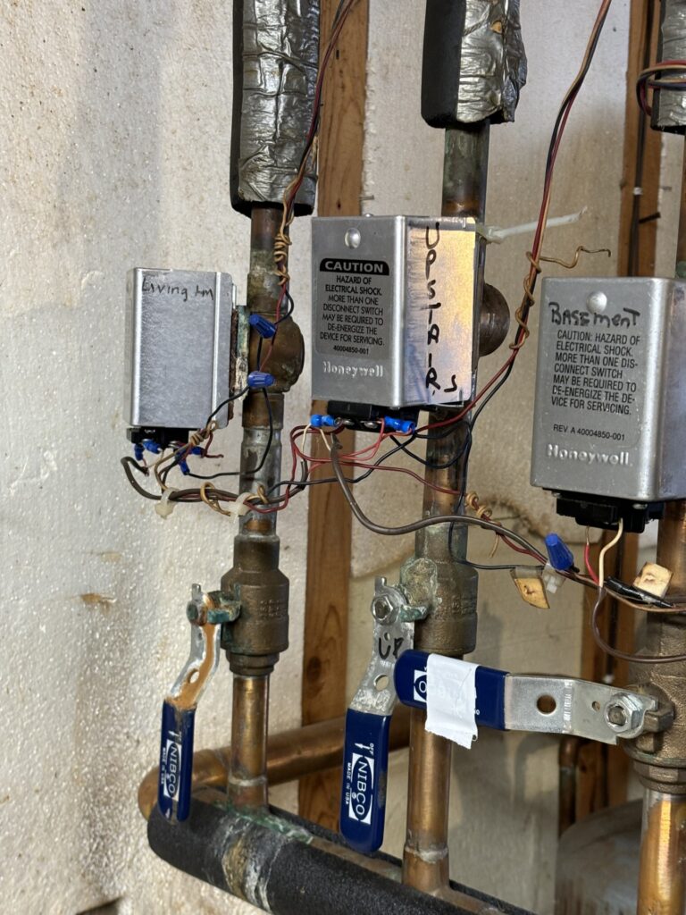 Multiple Honeywell zone valves installed on copper piping for hydronic boiler heating zones.