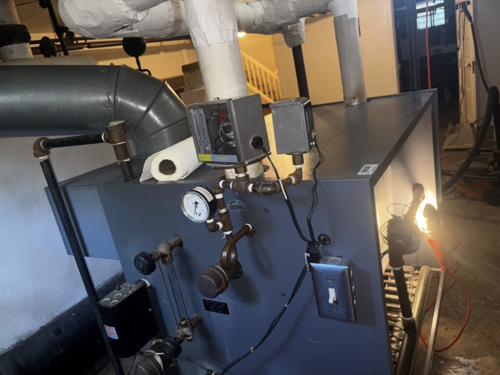 Close-up of steam boiler pressure gauge and control panel during maintenance service.