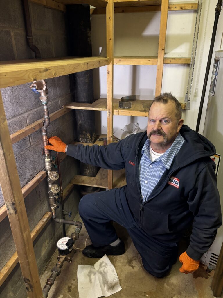 Licensed plumber inspecting vertical reduced pressure zone backflow preventer assembly.