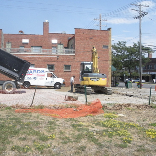 A picture of an excavator at a worksite with an Edwards Plumbing Heating and Cooling truck in the background