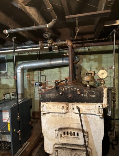 Commercial boiler system repair with venting and piping in basement mechanical room.