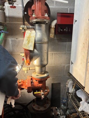 Edwards technician servicing a tagged fire-protection backflow preventer on a commercial sprinkler system in Northeast Ohio