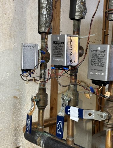 Multiple Honeywell zone valves installed on copper piping for hydronic boiler heating zones.