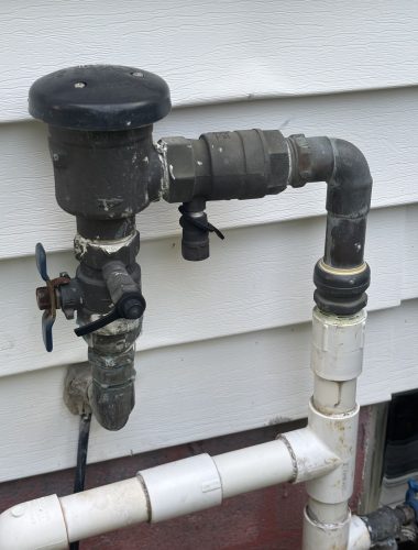 Exterior lawn-irrigation backflow preventer mounted on home siding, tested and certified by Edwards in Northeast Ohio