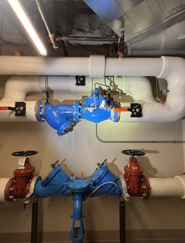 Large blue reduced-pressure backflow assembly with red gate valves on insulated commercial piping, tested by Edwards in Northeast Ohio