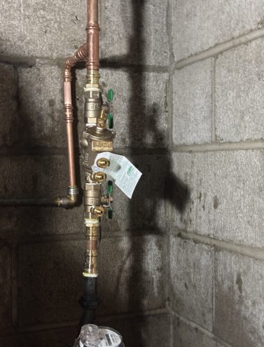 Newly installed brass backflow preventer with green Zurn shutoff valves on copper piping in a Northeast Ohio home basement