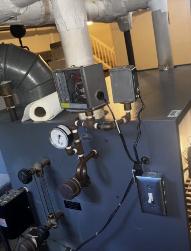 Close-up of steam boiler pressure gauge and control panel during maintenance service.