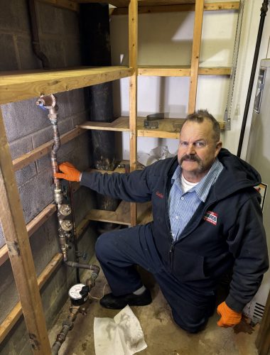 Licensed plumber inspecting vertical reduced pressure zone backflow preventer assembly.