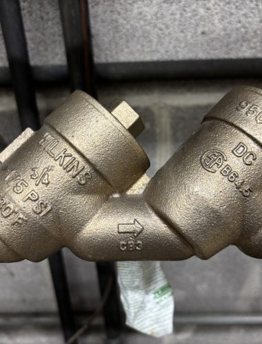 Close-up of a Wilkins 950XL2 brass double-check backflow assembly with green Zurn shutoff handles, serviced by Edwards in Northeast Ohio